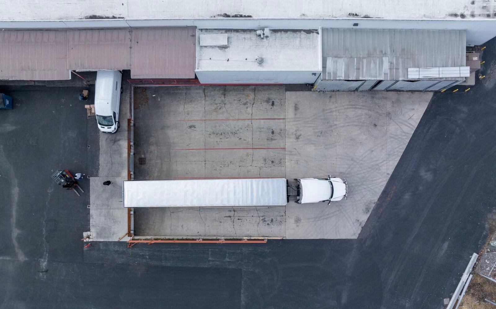 Aerial photo looking straight down on the outside of a warehouse with a semi truck parked in the lot.